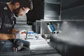一名佩戴安全裝備的人員正在安裝電線，一盞無線工作燈照亮了現場。