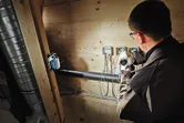 一名配戴安全裝備的人員正在無線燈附近連接電線盒。