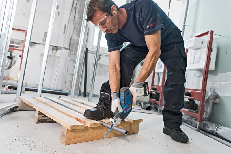 一名配戴安全設備的人員使用往復鋸切割金屬管路。.