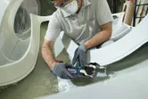 一名佩戴安全設備的人正在使用無線多功能工具切割玻璃纖維。