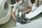 一名佩戴安全設備的人正在使用無線多功能工具切割玻璃纖維。.