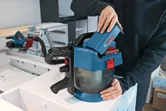 一個人將電池插入工作台上的無線除塵器。.