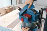 一個人將電池插入工作台上的無線除塵器。.