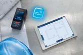 在顯示建築平面圖的數位平板電腦旁邊，用雷射測量藍圖。