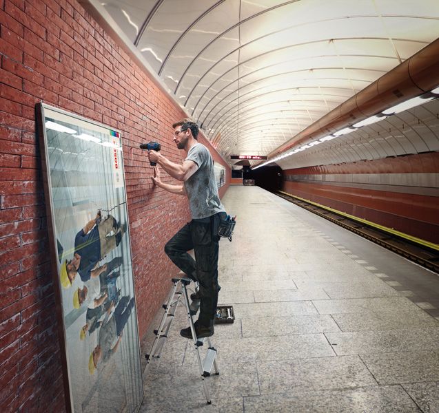 一名男子使用無線電鑽在地鐵站的磚牆上安裝框架。.