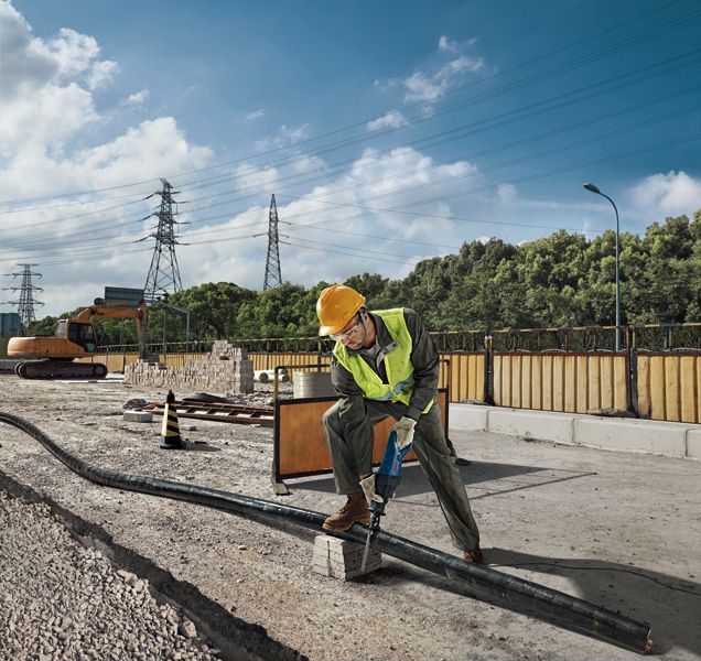 一名配戴安全設備的人員在工地使用往復鋸切割管道。.