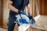 一名佩戴安全設備的人員使用圓鋸切割木板。.