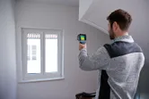 一名男子在室內使用熱成像攝影機掃描窗戶區域。