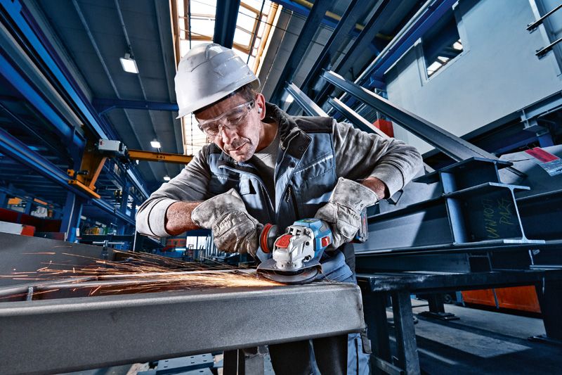 GWX 18V-15 SC 一名配戴安全設備的人員正在使用無線角磨機打磨金屬。.