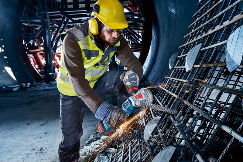 GWX 18V-15 SC 一名配戴安全設備的人員使用無線角磨機切割鋼筋。.