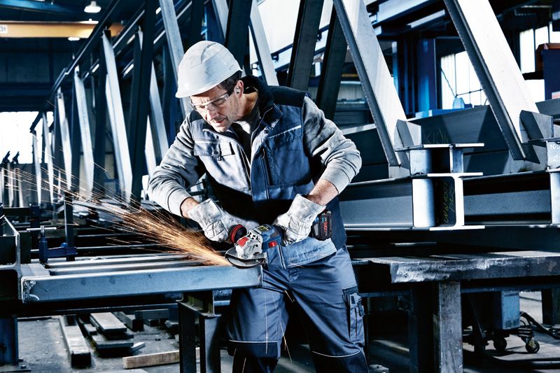 GWX 18V-15 SC 一名配戴安全設備的人員正在使用無線角磨機打磨金屬樑。.