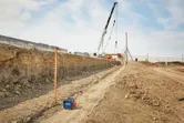 在建築工地上，靠近挖掘溝渠和起重機的地方正在使用雷射水平儀。