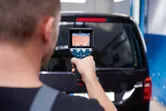 一名男子使用熱成像儀掃描黑色廂型車的後窗。