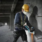 一名配戴安全設備的人員正在使用角磨機切割混凝土。