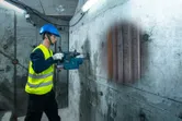 一名佩戴安全裝備的人員使用探測器掃描混凝土牆，以顯示其內部結構。