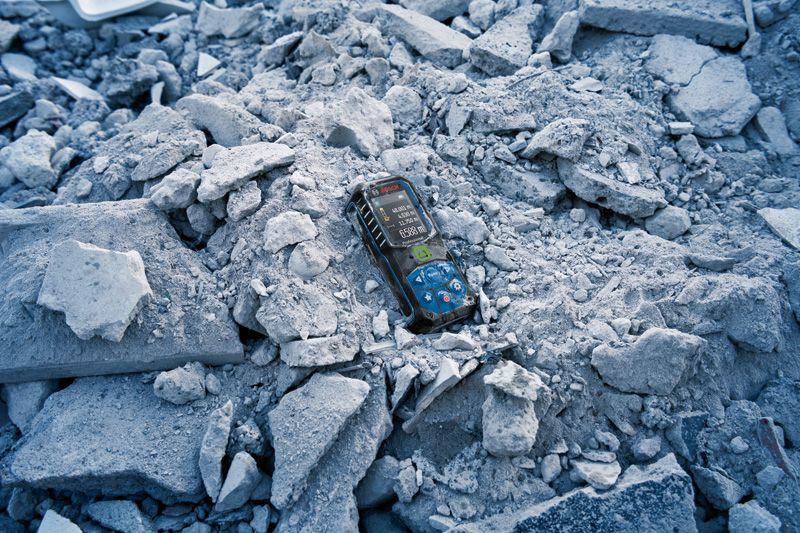 Laser measure resting on a pile of broken concrete rubble.