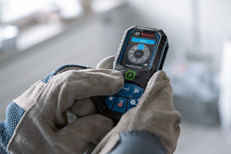 Person wearing safety equipment using a laser measure.