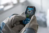 Person wearing safety equipment using a laser measure.