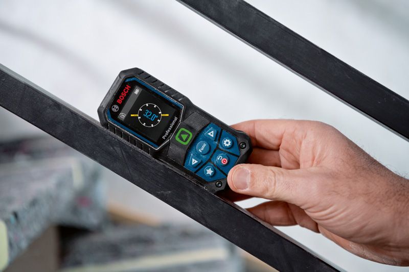 A person uses a laser measure to check the angle of a metal beam.
