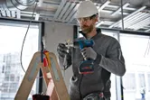 一名佩戴安全設備的人員使用無線熱風槍對電線進行加熱。