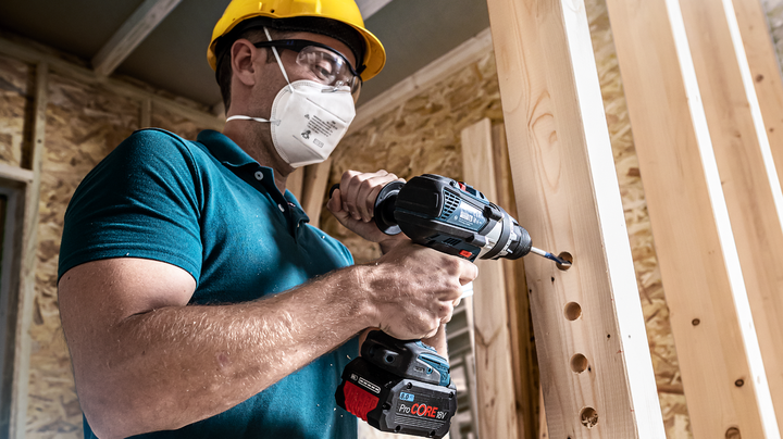 配戴安全設備的人員在木樑上鑽孔。