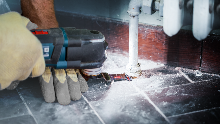EXPERT MetalMax AIZ 32 AIT 魔切機刀片 40 x 32 公釐 一名配戴安全設備的人員使用電動工具切割管道周圍的地板。