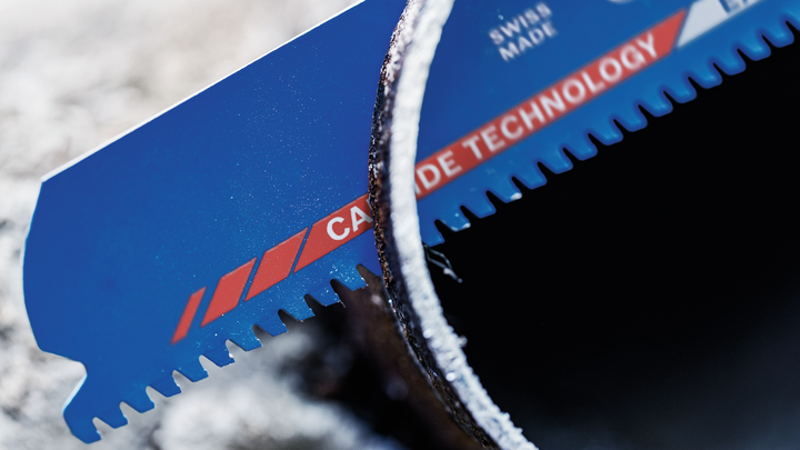 配戴安全設備的人員使用電動工具在戶外切割舊金屬管路。