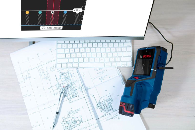 Detector device connected to a computer beside building plans and a keyboard.