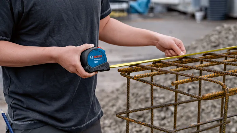 8m自動鎖定捲尺M 一個人用捲尺檢查金屬鋼筋結構的寬度。.