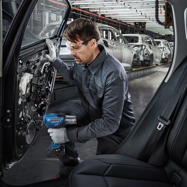 GRG 18V-16 C 一名配戴安全設備的工人在工廠生產線上使用電動工具組裝車門。.
