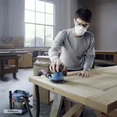 一名穿戴安全裝備的人員正在用電動砂光機打磨木板。