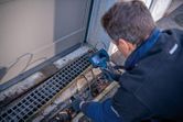 A person wearing safety equipment inspects a drain with an inspection camera.