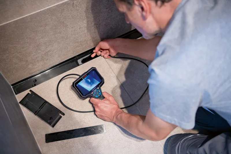 A person inspects inside a narrow space using an inspection camera.