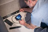 A person inspects inside a narrow space using an inspection camera.