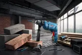 帶有鑽頭的衝擊鑽放置在建築工地被磚塊和木頭包圍的工作台上。.
