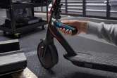 一個人用無線螺絲起子調整電動滑板車的車把。.