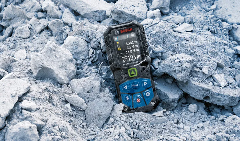 Laser measure lying on rubble at a construction site.