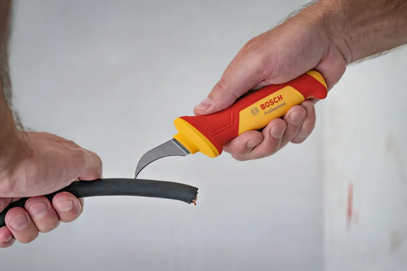 一個人用絕緣安全刀切開一根粗電纜。.