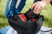 一個人在戶外將電池組插入無線割草機。