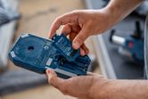 一個人將電池組插入藍色電動工具外殼。