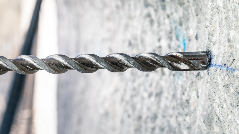 旋轉鎚鑽頭在混凝土牆上鑽孔。