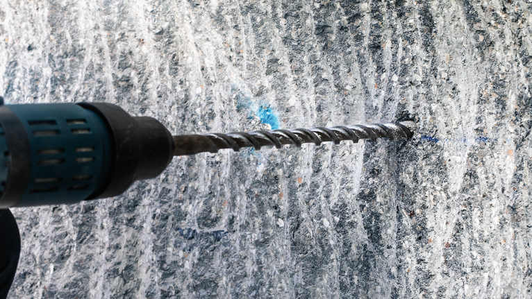 旋轉錘鑽入混凝土牆。