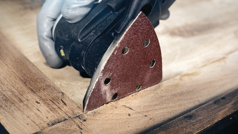 配戴安全設備的人員使用細節打磨機打磨木質表面。