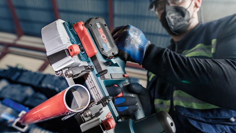 一名配戴安全設備的人員操作無線工具切割金屬管路。