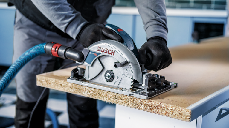 配戴安全設備的人員用圓鋸切割木板。