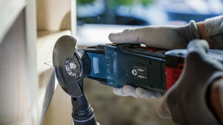 配戴安全設備的人使用電動工具切割木材。