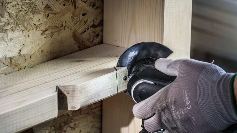 配戴安全設備的人員使用角磨機切割木樑。