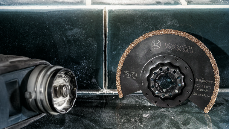 圓形硬質合金鋸片放置在電動工具旁的瓷磚表面上。