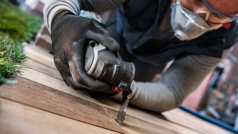 配戴安全設備的人員使用電動工具切割木板。