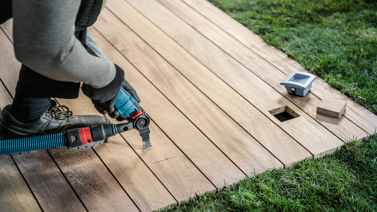 配戴安全設備的人員使用電動工具切割木質甲板。